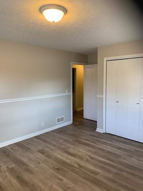 unfurnished bedroom featuring dark hardwood / wood-style flooring and a closet