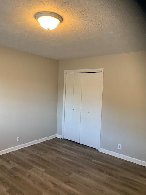 unfurnished bedroom with a closet, dark wood-type flooring, and a textured ceiling