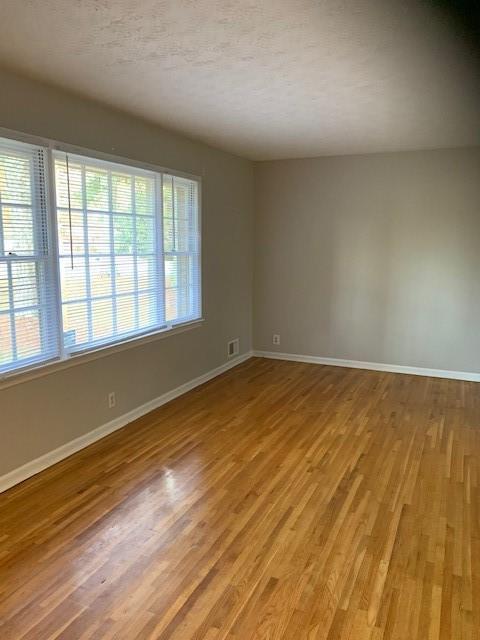 spare room with light hardwood / wood-style floors and a textured ceiling