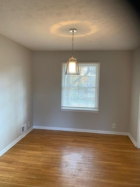 unfurnished room featuring hardwood / wood-style floors and a textured ceiling