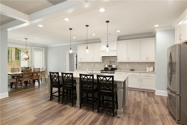 kitchen with appliances with stainless steel finishes, baseboards, crown molding, wood finished floors, and tasteful backsplash