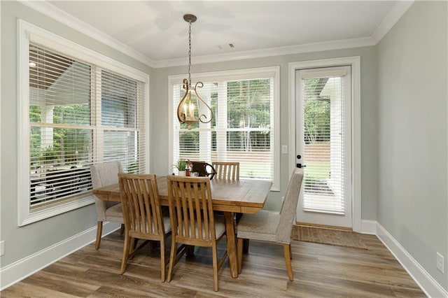 dining space featuring a chandelier, wood finished floors, crown molding, and baseboards