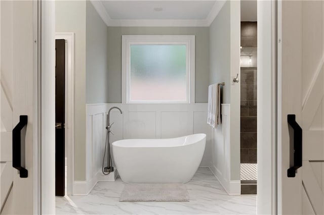 full bath with marble look tiles, a soaking tub, a tile shower, crown molding, and a wainscoted wall