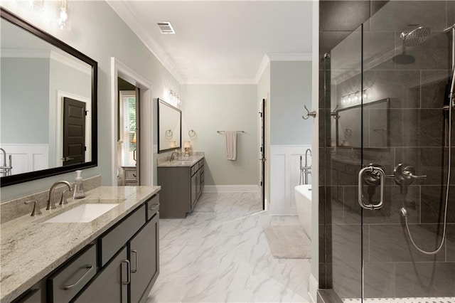 full bathroom with a shower stall, crown molding, a freestanding bath, a wainscoted wall, and two vanities
