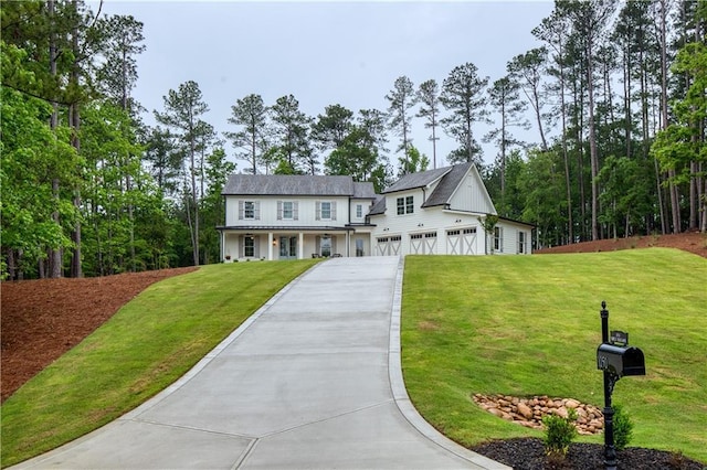 view of front facade featuring an attached garage, concrete driveway, a front yard, and covered porch