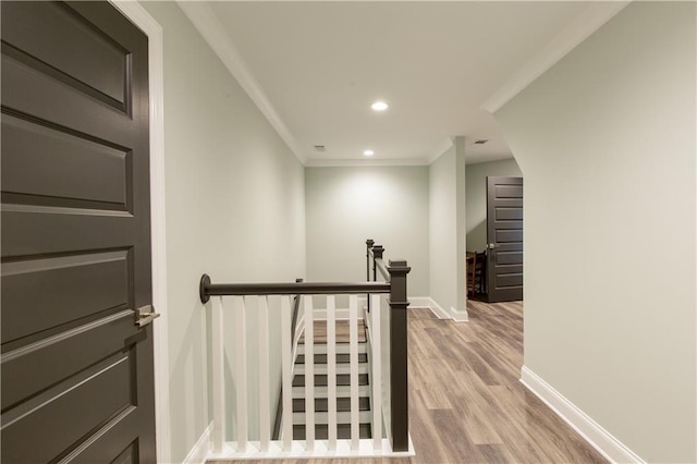 hallway featuring an upstairs landing, ornamental molding, wood finished floors, baseboards, and recessed lighting