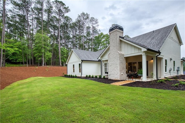 back of house with a chimney, a shingled roof, and board and batten siding
