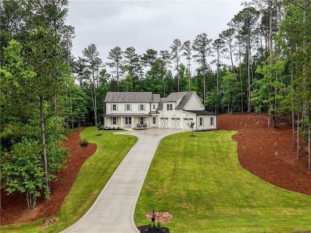 rear view of property with concrete driveway, a yard, and a garage