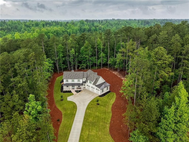 aerial view of property and surrounding area featuring a heavily wooded area