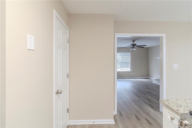 hallway featuring light wood-type flooring and baseboards