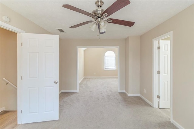 empty room featuring visible vents, light colored carpet, baseboards, and a textured ceiling