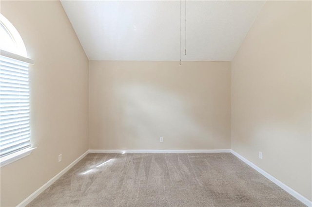 unfurnished room featuring baseboards, lofted ceiling, and light colored carpet