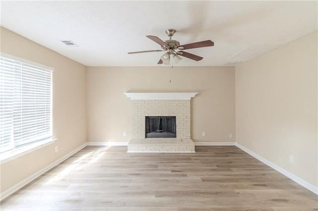 unfurnished living room with visible vents, a ceiling fan, light wood-style floors, a fireplace, and baseboards