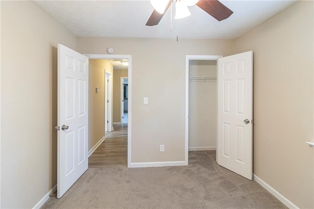 unfurnished bedroom featuring a ceiling fan, baseboards, a closet, and light carpet