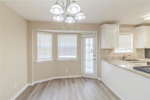 kitchen with a sink, baseboards, light wood finished floors, and white cabinetry