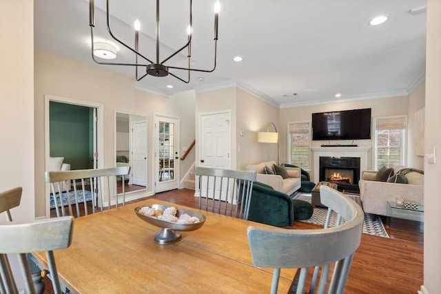 dining space with hardwood / wood-style flooring, ornamental molding, and an inviting chandelier