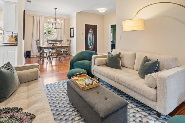 living room featuring crown molding, hardwood / wood-style floors, and an inviting chandelier