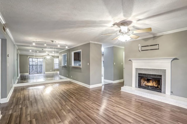 unfurnished living room with wood-type flooring, crown molding, and a brick fireplace