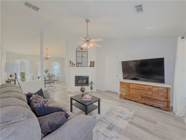 living room featuring light wood-type flooring, ceiling fan with notable chandelier, and lofted ceiling