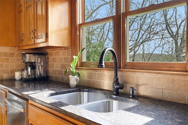 kitchen featuring dark stone countertops, dishwasher, sink, and backsplash