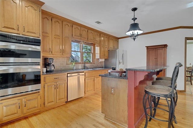 kitchen featuring a kitchen bar, sink, a center island, ornamental molding, and appliances with stainless steel finishes