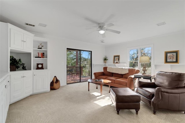 living room with light carpet, built in shelves, and ceiling fan