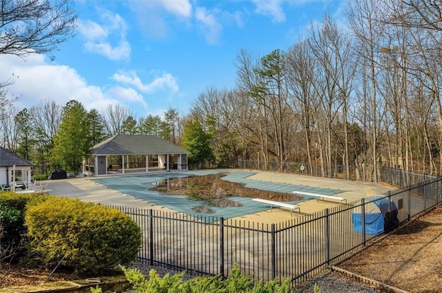 view of pool with a diving board, an outdoor structure, and a patio area