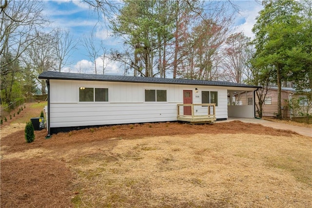 ranch-style home with cooling unit, a carport, board and batten siding, and driveway