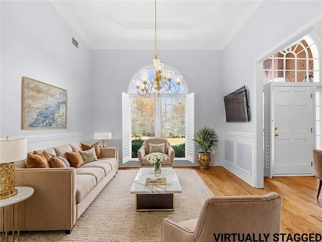 living room featuring ornamental molding, a chandelier, and light hardwood / wood-style floors