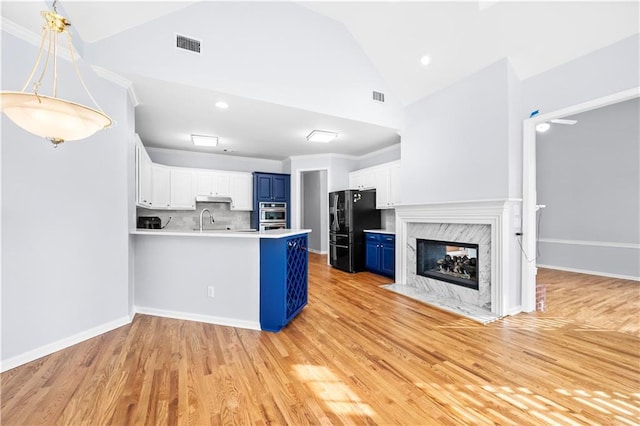 kitchen with blue cabinets, white cabinetry, sink, kitchen peninsula, and black fridge