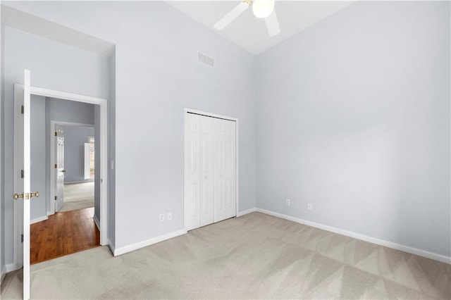 unfurnished bedroom with light carpet, ceiling fan, and a closet