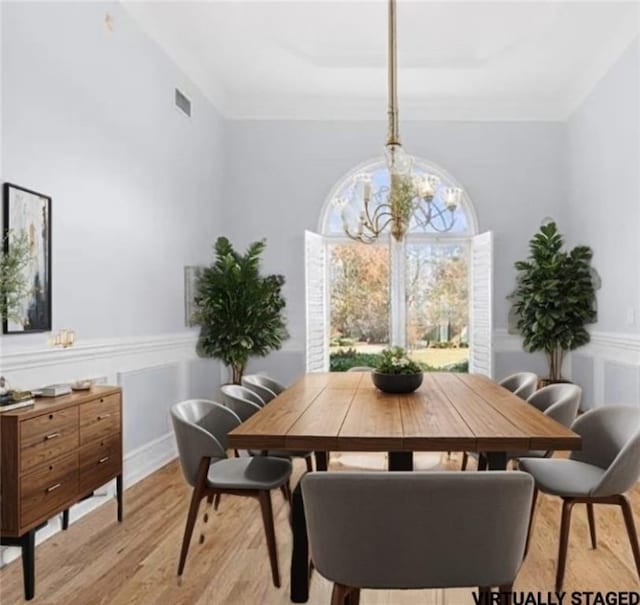 dining room featuring ornamental molding, light wood-type flooring, and a notable chandelier