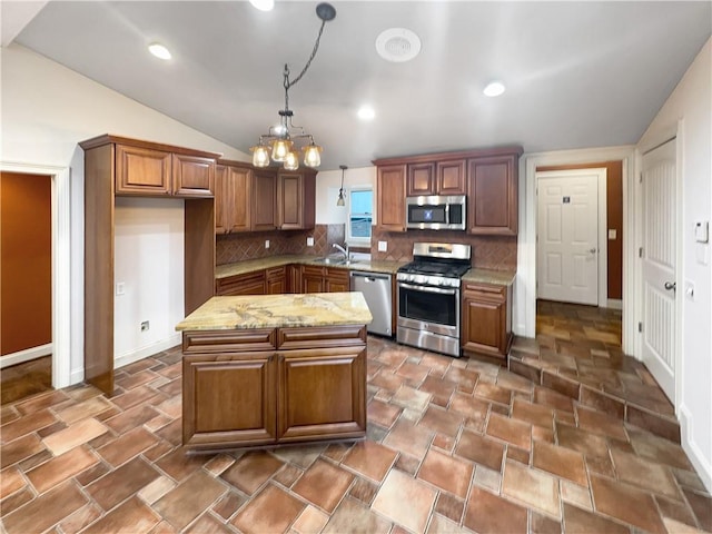 kitchen featuring tasteful backsplash, vaulted ceiling, appliances with stainless steel finishes, decorative light fixtures, and light stone countertops