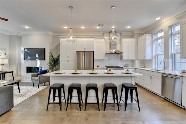 kitchen featuring a breakfast bar, white cabinetry, hanging light fixtures, stainless steel appliances, and a center island