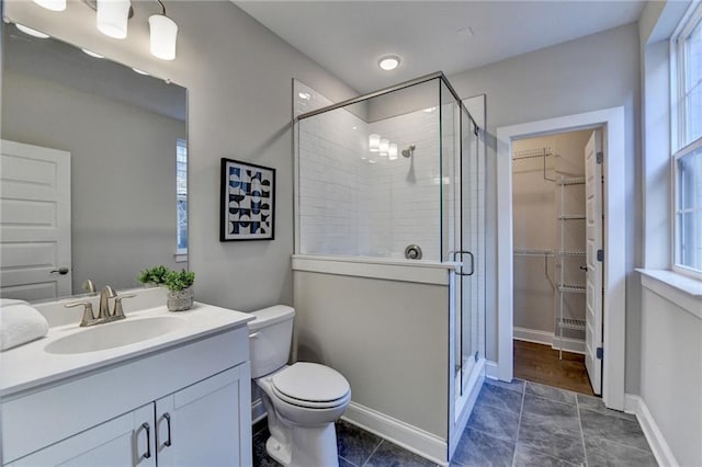 bathroom with walk in shower, vanity, toilet, and a wealth of natural light