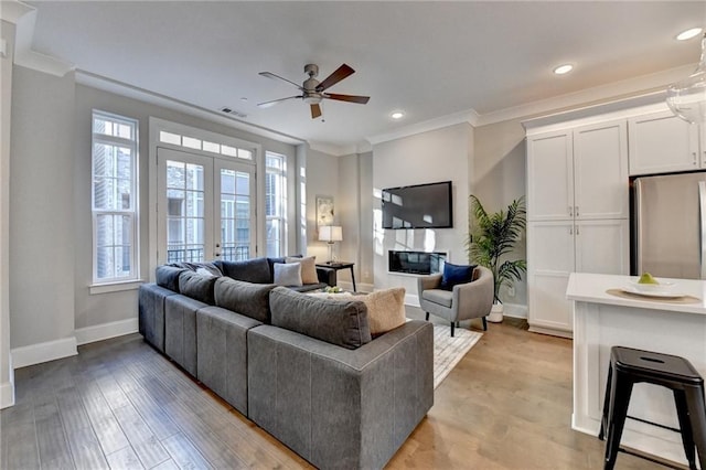 living room featuring crown molding, light hardwood / wood-style flooring, french doors, and ceiling fan