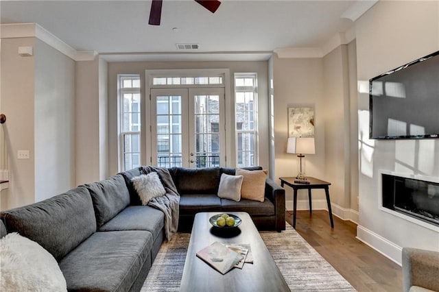 living room with wood-type flooring, ornamental molding, french doors, and ceiling fan