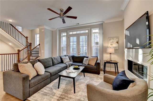 living room featuring ornamental molding, french doors, ceiling fan, and light wood-type flooring