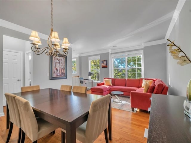 dining space featuring light hardwood / wood-style flooring, a notable chandelier, and crown molding