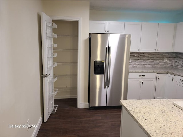 303 Tara Commons Cir, Loganville, GA 30052 - kitchen with stainless steel fridge with ice dispenser, dark wood-type flooring, white cabinetry, tasteful backsplash, and light stone countertops
