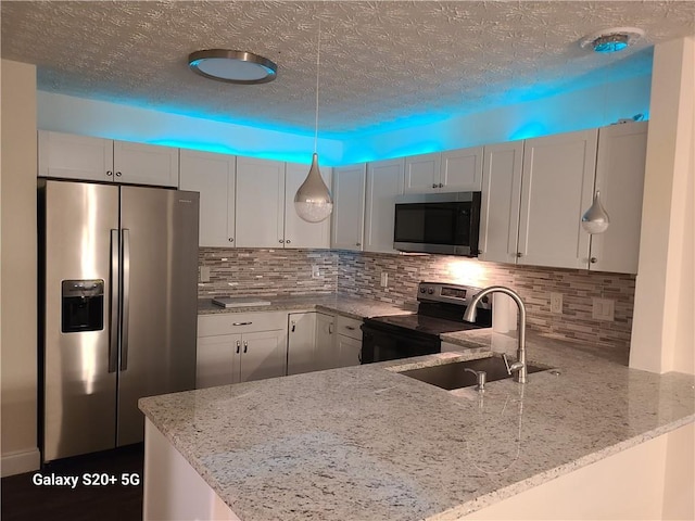 303 Tara Commons Cir, Loganville, GA 30052 - kitchen with appliances with stainless steel finishes, light stone countertops, backsplash, a peninsula, and a textured ceiling