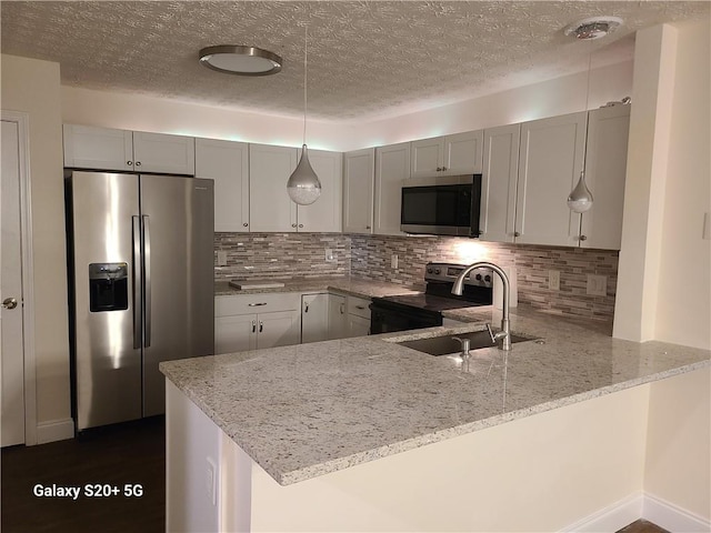303 Tara Commons Cir, Loganville, GA 30052 - kitchen featuring appliances with stainless steel finishes, a peninsula, light stone counters, tasteful backsplash, and a textured ceiling