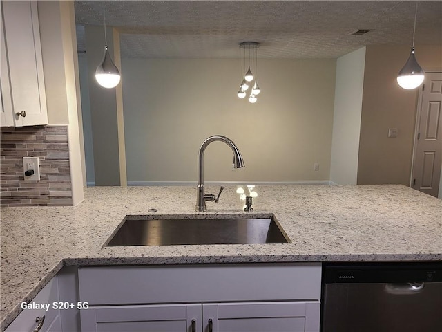 303 Tara Commons Cir, Loganville, GA 30052 - kitchen with dishwasher, tasteful backsplash, light stone countertops, decorative light fixtures, and a textured ceiling