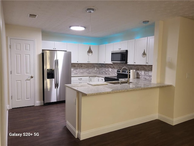 303 Tara Commons Cir, Loganville, GA 30052 - kitchen with stainless steel appliances, a peninsula, light stone countertops, dark wood-style flooring, and tasteful backsplash