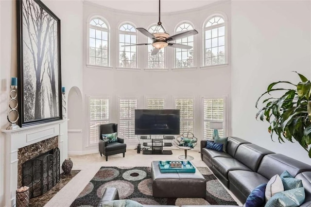 carpeted living room featuring ceiling fan, crown molding, and a high end fireplace