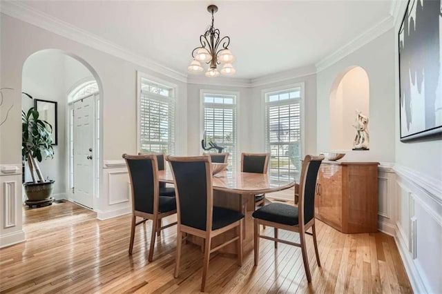 dining space with a notable chandelier, ornamental molding, and light wood-type flooring