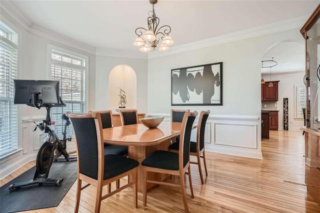 dining area featuring crown molding, light hardwood / wood-style flooring, and a chandelier