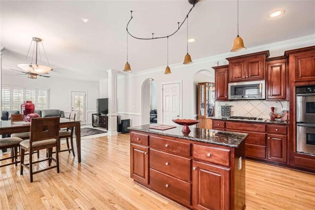 kitchen with light hardwood / wood-style flooring, stainless steel appliances, ornamental molding, and decorative light fixtures