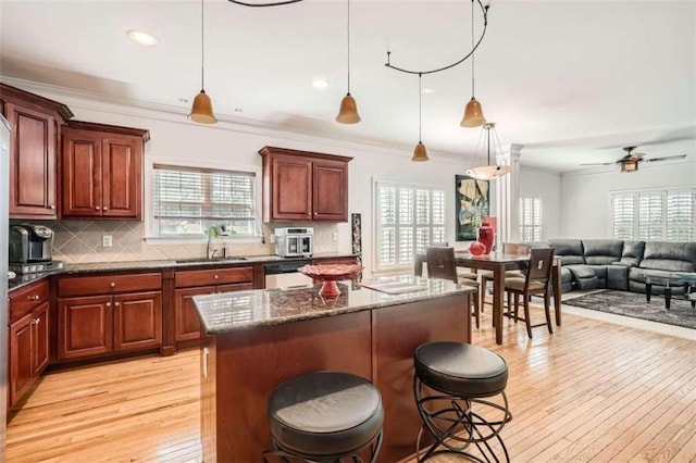 kitchen featuring a breakfast bar area, light hardwood / wood-style flooring, decorative light fixtures, and a kitchen island