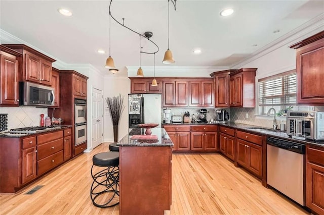 kitchen with light hardwood / wood-style flooring, stainless steel appliances, crown molding, sink, and a center island